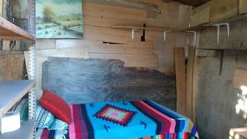 A rustic room with a wooden bed, a colorful blanket, and a painting on the wall.