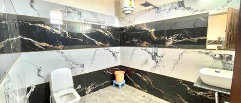 Une salle de bain équipée de toilettes, d’un bidet et d’un lavabo, avec des murs en marbre noir et blanc et un design moderne.