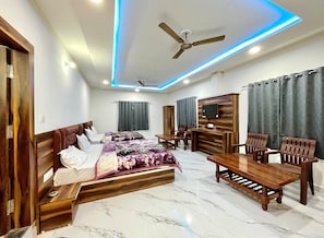 A modern bedroom with a bed, bedside tables, a desk, and a TV.