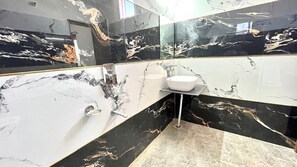A bathroom with a white sink, black and white marble walls, and a mirror.