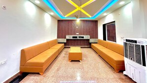 A modern living room with a sofa set, a coffee table, and a wall-mounted entertainment unit. - manya palace (Orchha)
