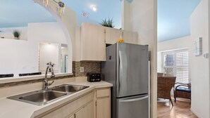 A modern kitchen with stainless steel appliances, a double sink, and light wooden cabinetry.