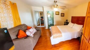 A bedroom with a bed, a sofa, and a ceiling fan. - Roatan Airport Boutique Resort (Coxen Hole)