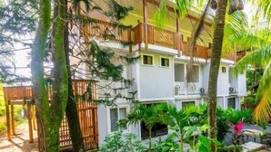 A multi-story building with balconies, surrounded by lush tropical vegetation. - Roatan Airport Boutique Resort (Coxen Hole)