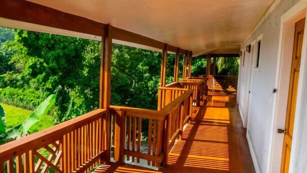 A covered corridor with wooden railings, leading to a door on the right. - Roatan Airport Boutique Resort (Coxen Hole)