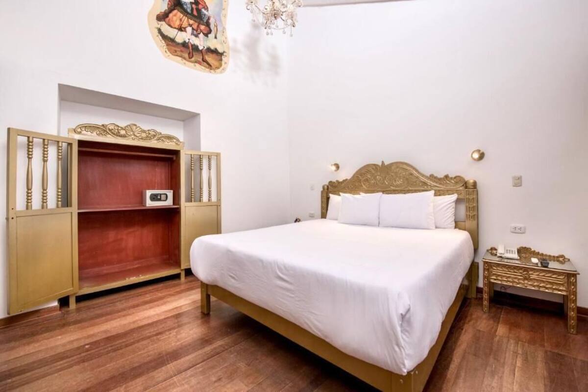 A bedroom with a bed, wooden wardrobe, and a small bedside table.