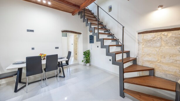 A modern interior with a staircase, a dining area, and a stone wall. - Nikos StoneHouse family home, located in the center of Prines (Rethymno)