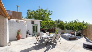 A patio with a dining table and chairs, a sofa, and a small bed. - Nikos StoneHouse family home, located in the center of Prines (Rethymno)