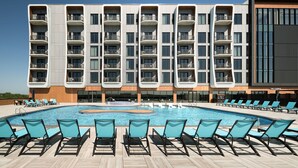 Un hôtel moderne doté d’une piscine, de nombreux balcons et de chaises longues.
