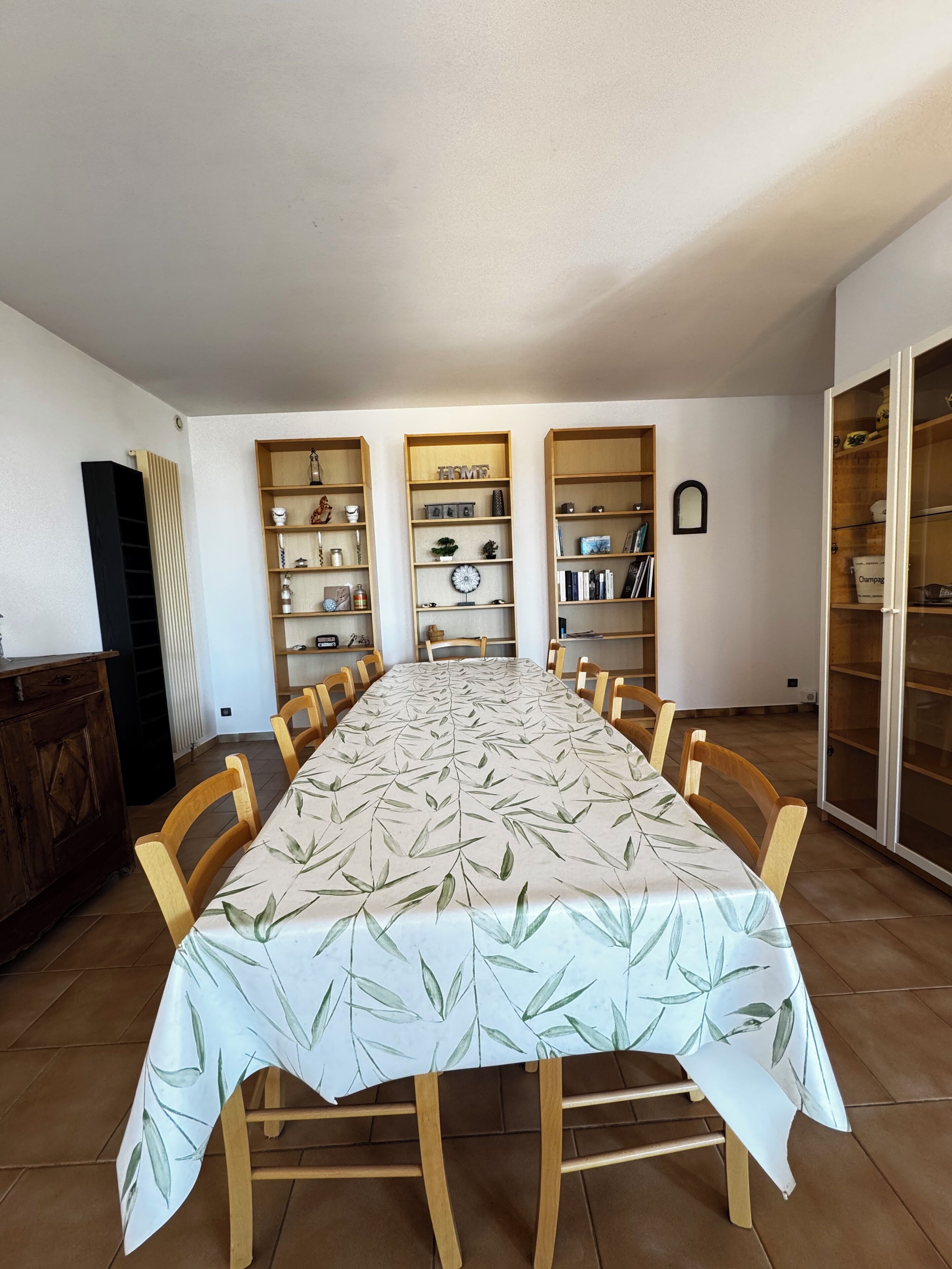 Un comedor con una larga mesa, sillas de madera y estanterías empotradas.