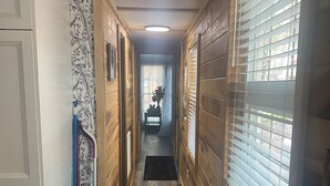 Un pasillo estrecho con paredes y suelo de madera, que lleva a una puerta al final.