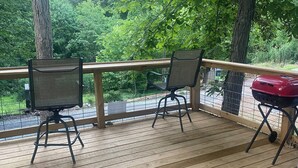 Una terraza de madera con dos sillas y una parrilla.
