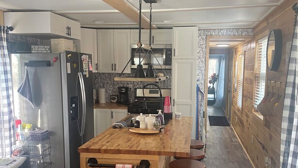 Una cocina con una isla central, armarios de madera, un refrigerador y un microondas.