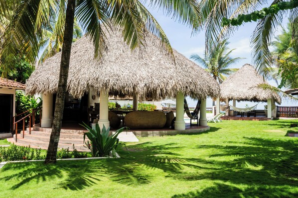 A resort with thatched-roof structures, a pool area, and lush greenery.