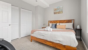 Un dormitorio con una cama de madera, paredes blancas y un cuadro sobre la cama.