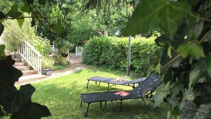A backyard with a grassy lawn, two black lounge chairs, a white fence, and a staircase leading to a house. - Family home between sea and countryside for 6 people (aubigny)