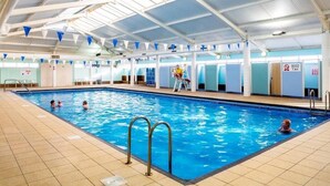 Ein Hallenbad mit klarem Wasser, gefliestem Boden und einer Decke mit blauen dreieckigen Wimpeln.