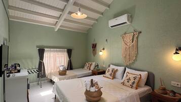 A hotel room with two beds, a desk, a small kitchenette, and a large window.