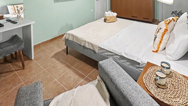 A bedroom with a bed, a desk, a television, a wardrobe, and a bedside lamp. - Hanole Macaron Guest House (Ayvalik)