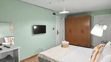 Ein Schlafzimmer mit Bett, Schreibtisch, Fernseher, Kleiderschrank und Nachttischlampe.