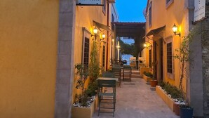 A building with a sign reading 'HANOE MACARON GUEST HOUSE' and a paved courtyard with outdoor seating. - Hanole Macaron Guest House (Ayvalik)