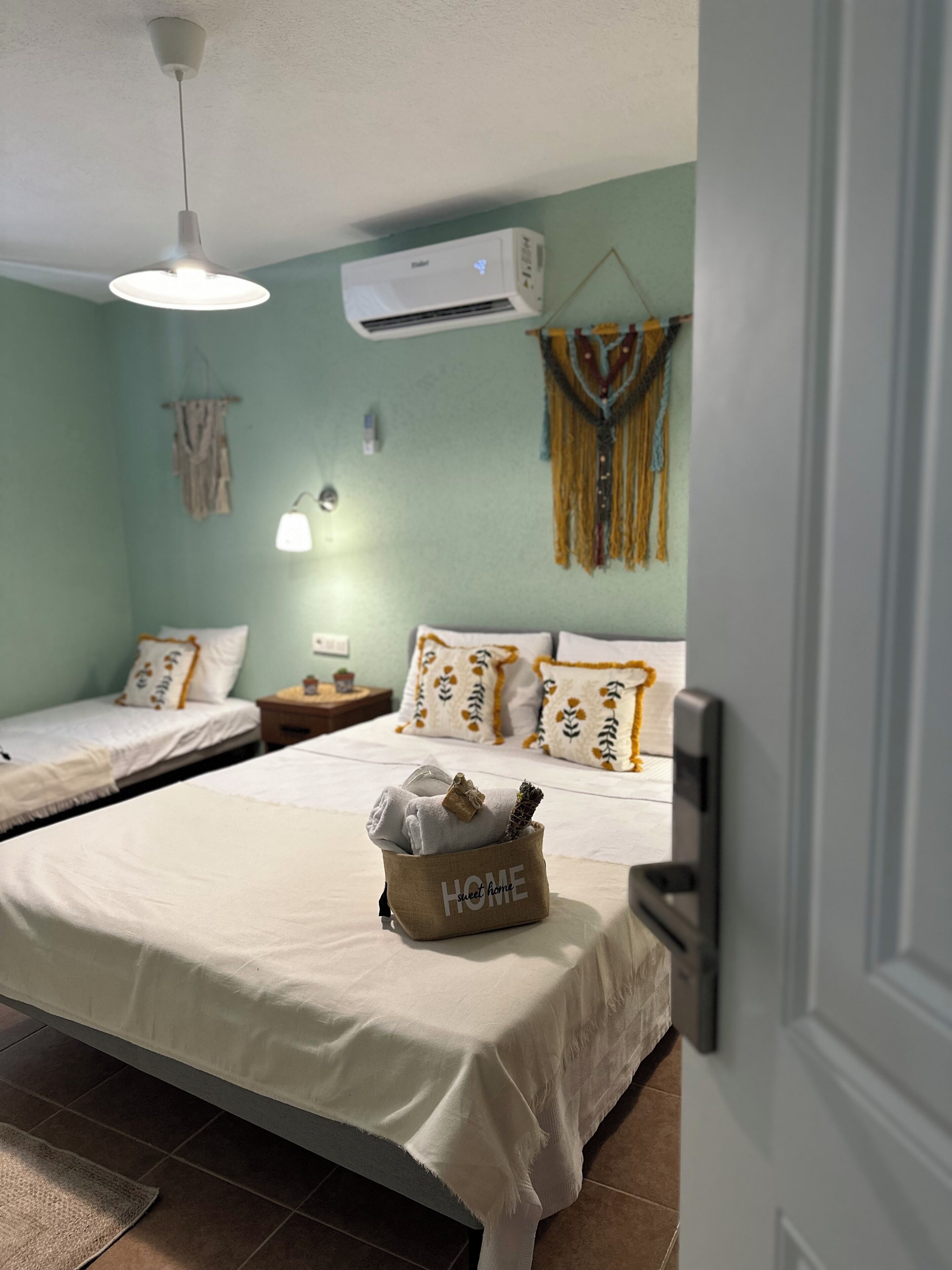 Habitación de hotel con dos camas, una lámpara colgante, un equipo de aire acondicionado y un adorno en la pared.