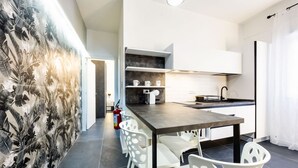 A modern kitchen with white cabinets, a dark countertop, and a dining area with white chairs. - Palermo | Calatafimi House (Palermo)