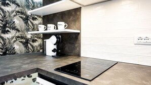 A modern kitchen with a black countertop, white backsplash, and a wall-mounted coffee machine. - Palermo | Calatafimi House (Palermo)