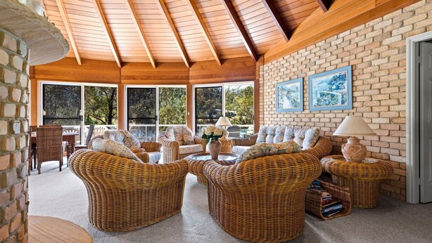 A cozy room with wicker furniture, large windows, and a brick wall.