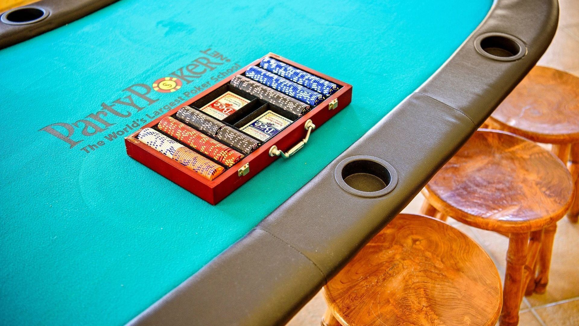 Une table de poker avec une boîte rouge contenant des jetons de poker et une pancarte sur laquelle on peut lire « PartyPoker ».