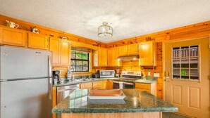 A kitchen with wooden cabinets, a granite countertop, a refrigerator, a stove, and a window. - 3 miles to Dollywood! Mountain views! Hot tub! Family fun! (Sevierville)
