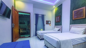 A hotel room with two beds, a TV, a door leading to a balcony, and a green textured wall. - Morobudur Guesthouse (Borobudur)