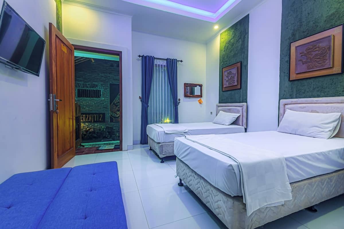 A hotel room with two beds, a TV, a door leading to a balcony, and a green textured wall.