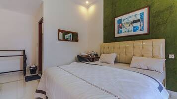 A hotel room with a large bed, a bedside table with a lamp, a framed picture on the wall, and a green accent wall.