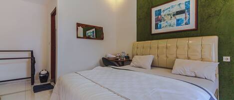 Habitación de hotel con una cama grande, una mesita de noche con lámpara, un cuadro enmarcado en la pared y una pared verde decorativa.