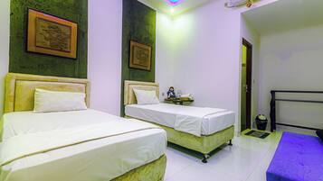 A hotel room with two beds, a small table, and a bench.