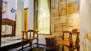 A room with a large mirror, two wooden chairs, a small table, and a decorative wall panel. - Morobudur Guesthouse (Borobudur)