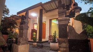A traditional building with a stone entrance, a wooden door, and a small garden area with potted plants. - Morobudur Guesthouse (Borobudur)