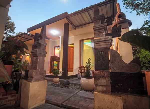 A traditional building with a stone entrance, a wooden door, and a small garden area with potted plants. - Morobudur Guesthouse (Borobudur)