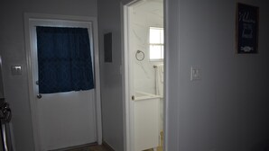 A hallway with a white door, a blue curtain, and a sign that reads "Welcome to the beach". - Ocean View Studio - #7 (George Town)