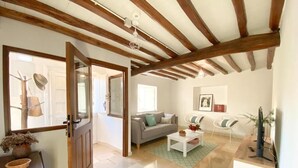 Un amplio salón con techo de madera, un sofá, una mesa de centro y un televisor.