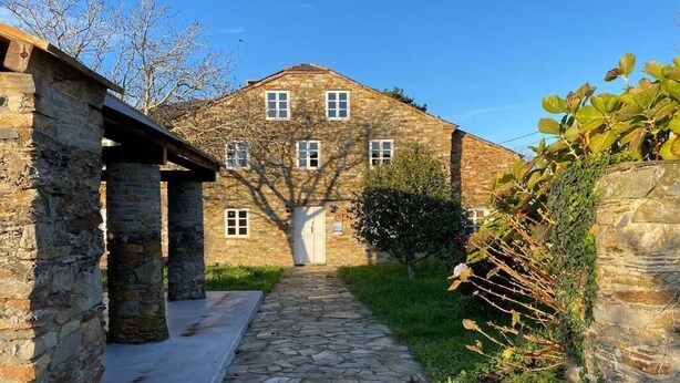 Un edificio de piedra con un camino de piedra que conduce a una puerta blanca.