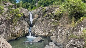 Ein Wasserfall in einer felsigen Schlucht, umgeben von üppigem Grün.