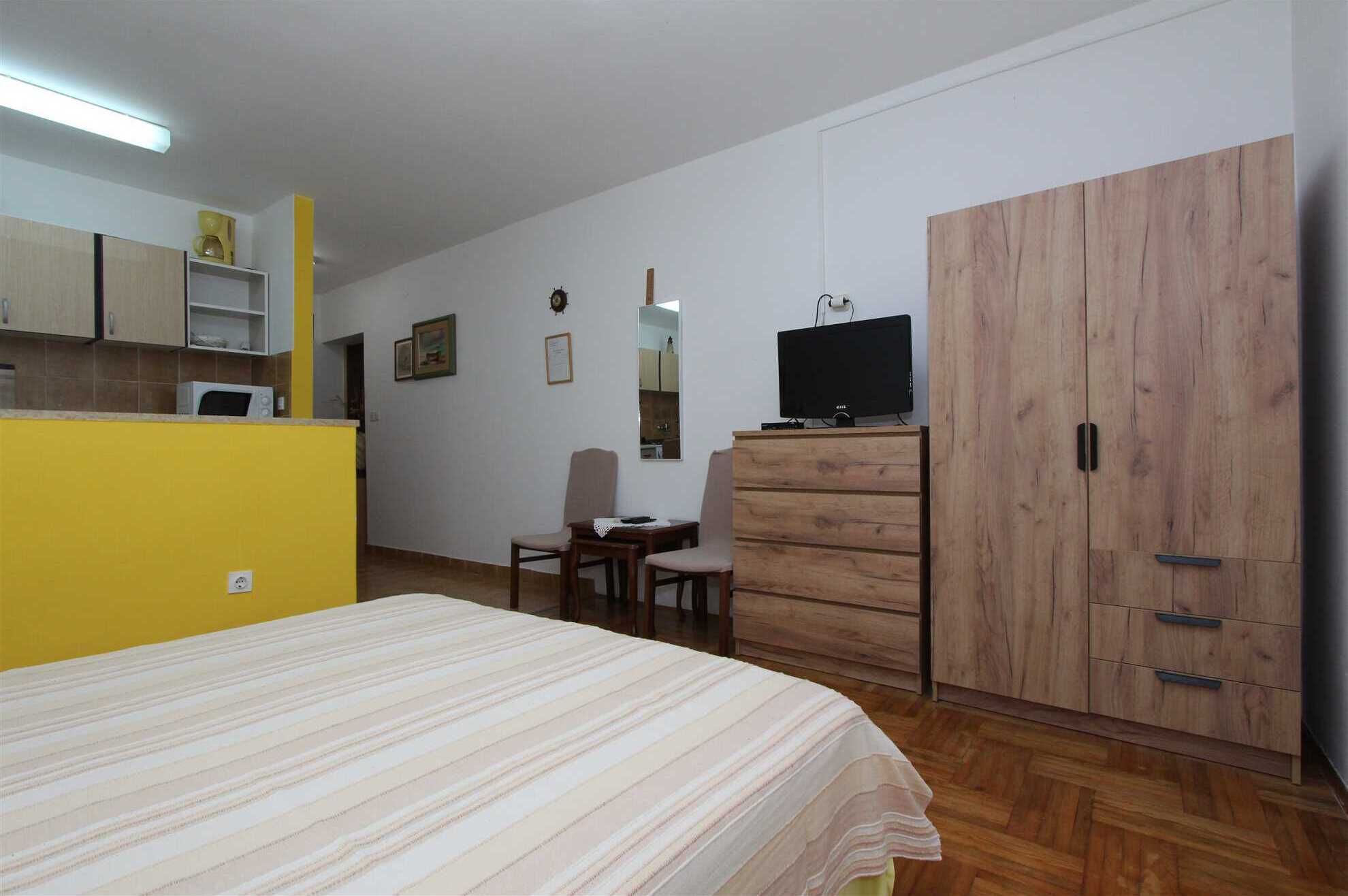 Une chambre à coucher comprenant un lit, une armoire en bois, une télévision, un bureau et une chaise.