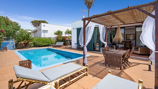 A pool area with lounge chairs and a covered seating area.