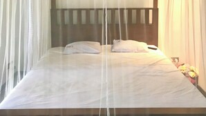 A bed with a wooden headboard and white bedding, surrounded by sheer curtains. - Relax in nature at ''Mount Heaven Araliya''Comfort, privacy, and calm await! (Hikkaduwa)