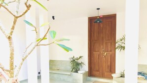 A room with a wooden door, a potted plant, a bench, and a hanging light fixture. - Relax in nature at ''Mount Heaven Araliya''Comfort, privacy, and calm await! (Hikkaduwa)