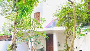 A white building with a red roof, a wooden door, and a small porch area with potted plants. - Relax in nature at ''Mount Heaven Araliya''Comfort, privacy, and calm await! (Hikkaduwa)