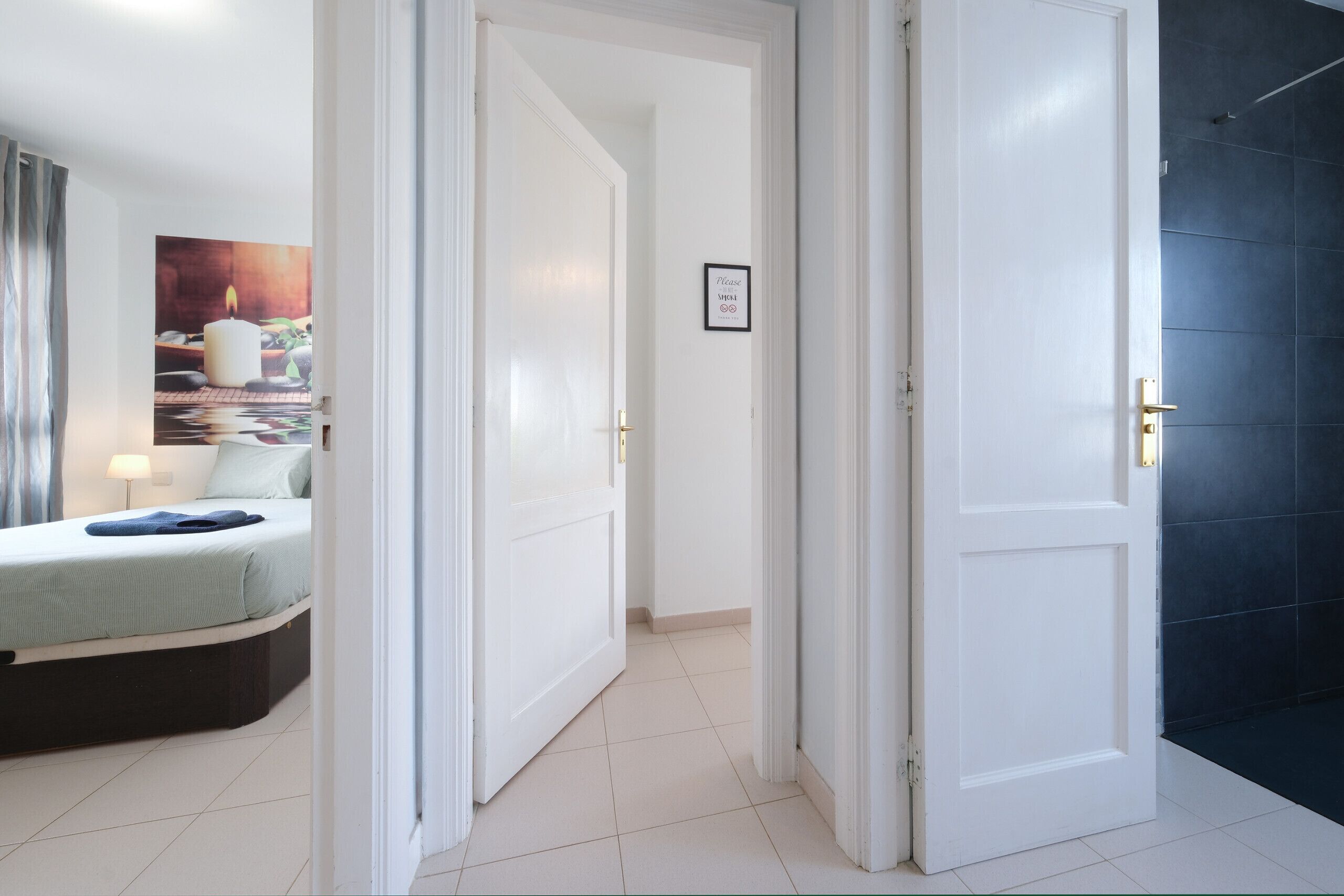 Une chambre d’hôtel avec un lit, un tableau, une porte et un sol carrelé.