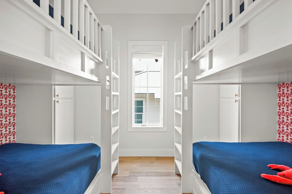 A narrow hallway with two beds on either side, white lockers, and a window at the end.